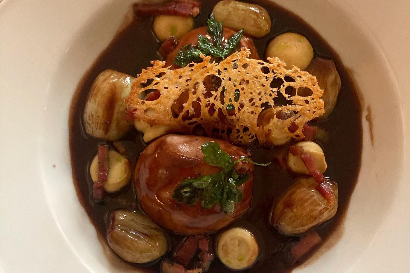 Chez Annette, à Paris, l’œuf poché « est enveloppé dans une soyeuse sauce au vin et le jaune crémeux crée un sillon dans le rouge brun de la sauce »